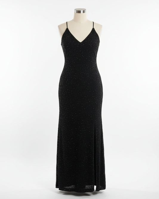 Woman in a black dress standing against a wall with decorative plates.