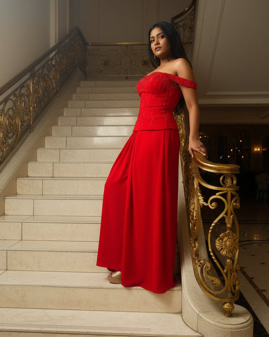 Person wearing a red off-shoulder dress standing on a staircase.