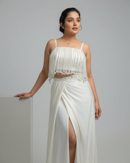 Woman wearing a white dress with a high slit on a gray background