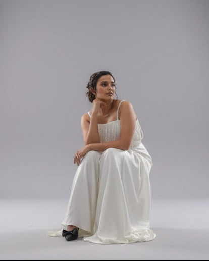 Woman in a white dress sitting on a gray background