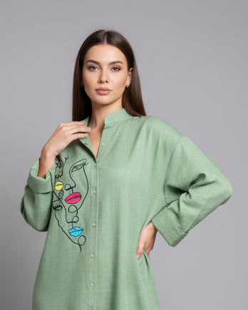 Green kurta with face design and colorful lips on a mannequin against a plain background