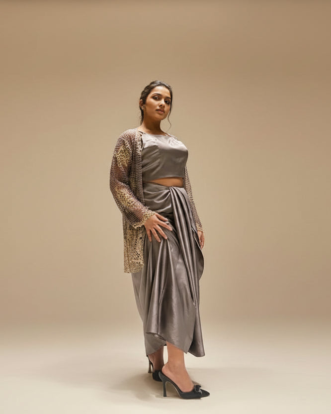 Woman in a gray outfit standing against a textured wall