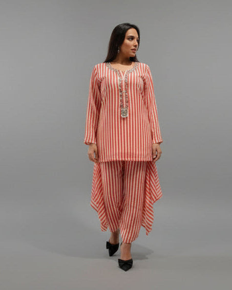 Woman in a pink outfit standing in an elevator with marble floor and gold accents.