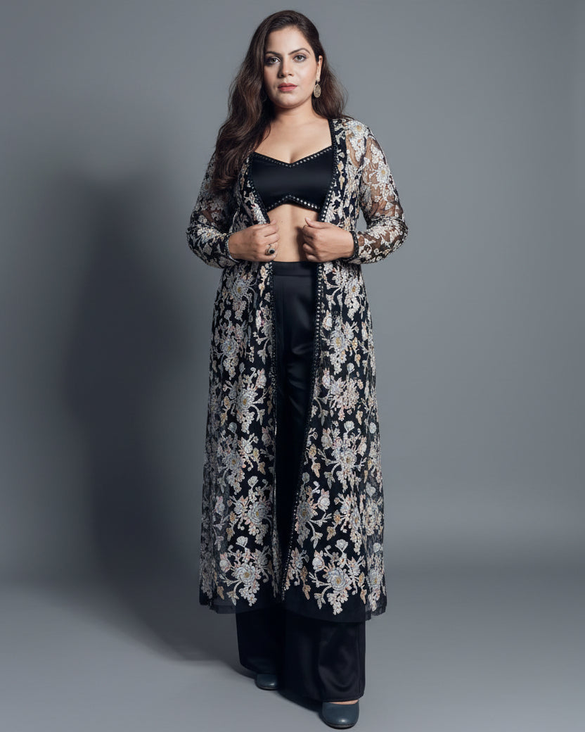 Woman wearing a black and white floral kimono over a black outfit with a bicycle and plant in the background.