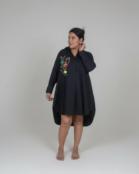 Person wearing a black dress with colorful embroidery on a white background