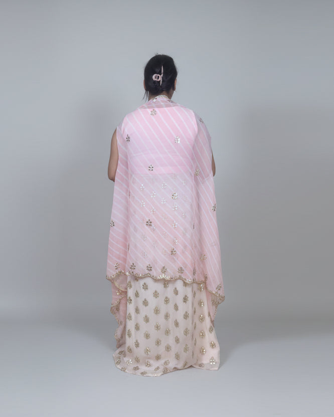 Person wearing a pink saree standing in a room with tiled floor and white walls.