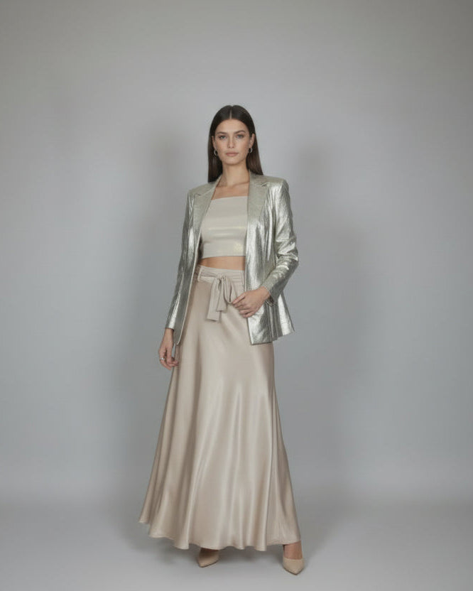 Mannequin wearing a metallic jacket and beige pants in a room with doors and tiled floor.