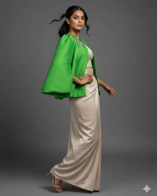Woman wearing a green cape over a white top and beige skirt on a gray background