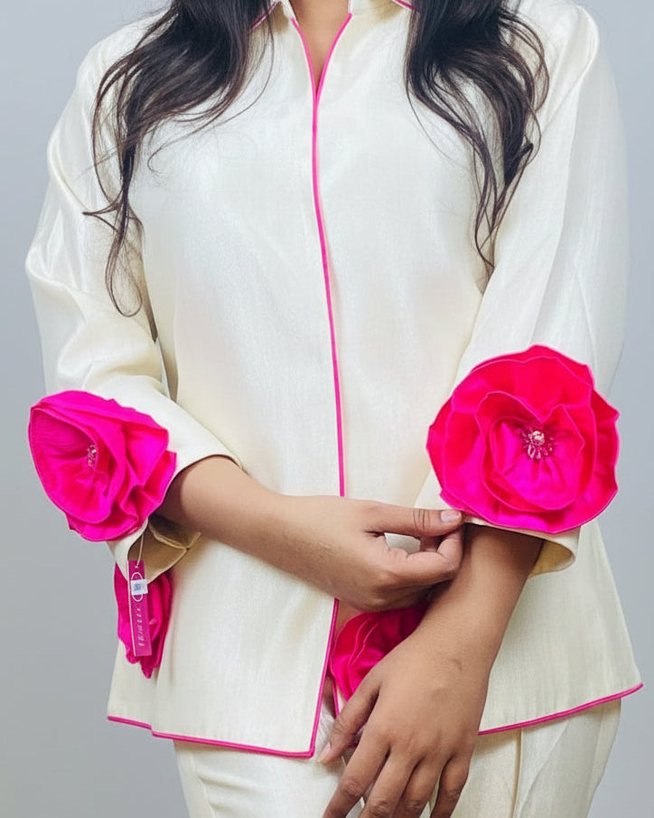 Person wearing a white outfit with pink floral embellishments on a plain background