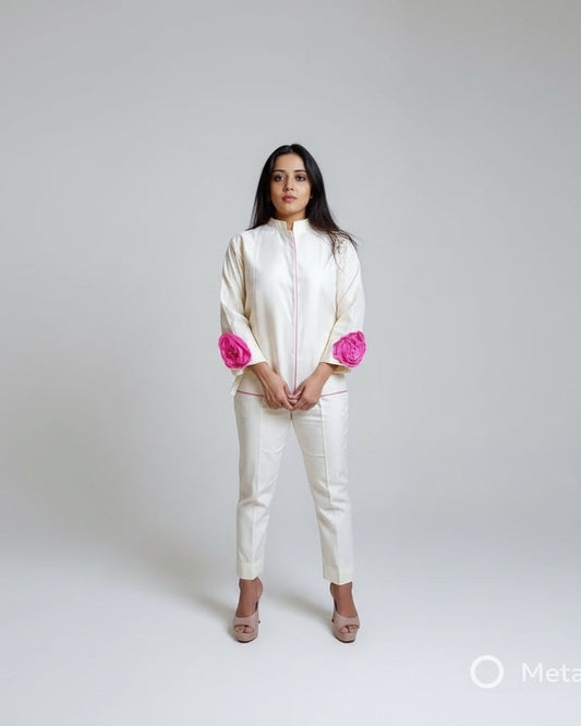 Woman wearing a white outfit with pink accents against a plain background